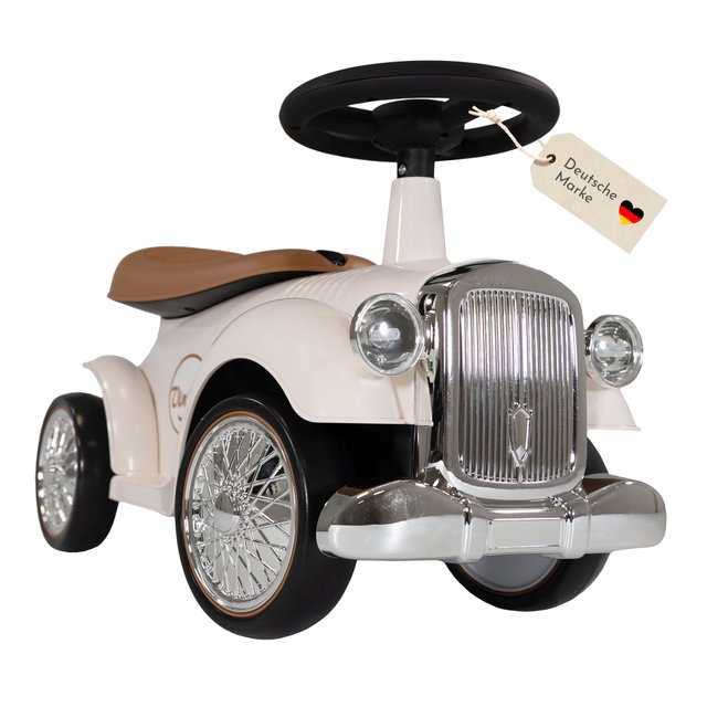 Weißes Rutschauto im Retrodesign mit schwarzem Lenkrad, braunem Sitz und Chrom-Optik an Front und Rädern