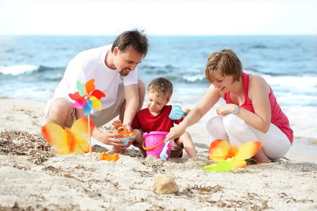 bollerwagen-strand vater und mutter spielen mit kind am sand, ostsee