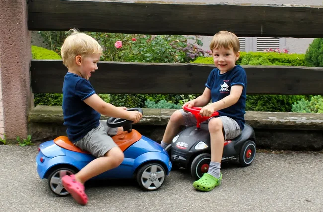 zwei jungs fahren mit rutschautos