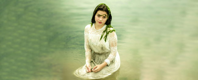 poolplatz.de-blog-poolpflege frau in weißem kleid sitst im wasser, bedeckt mit algen