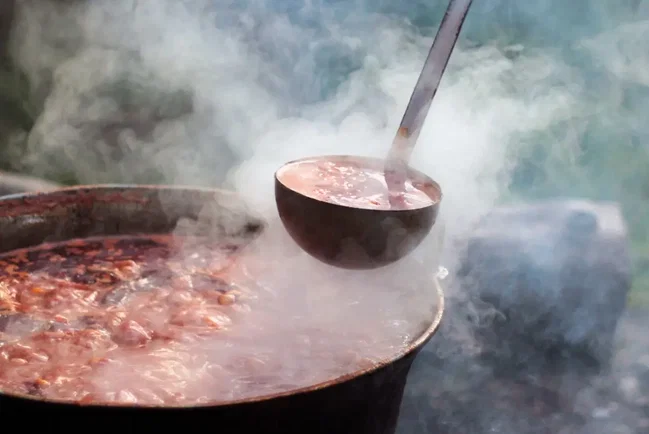 gulaschkanone dampfendes gulasch wird aus der gulaschkanone geschöpft
